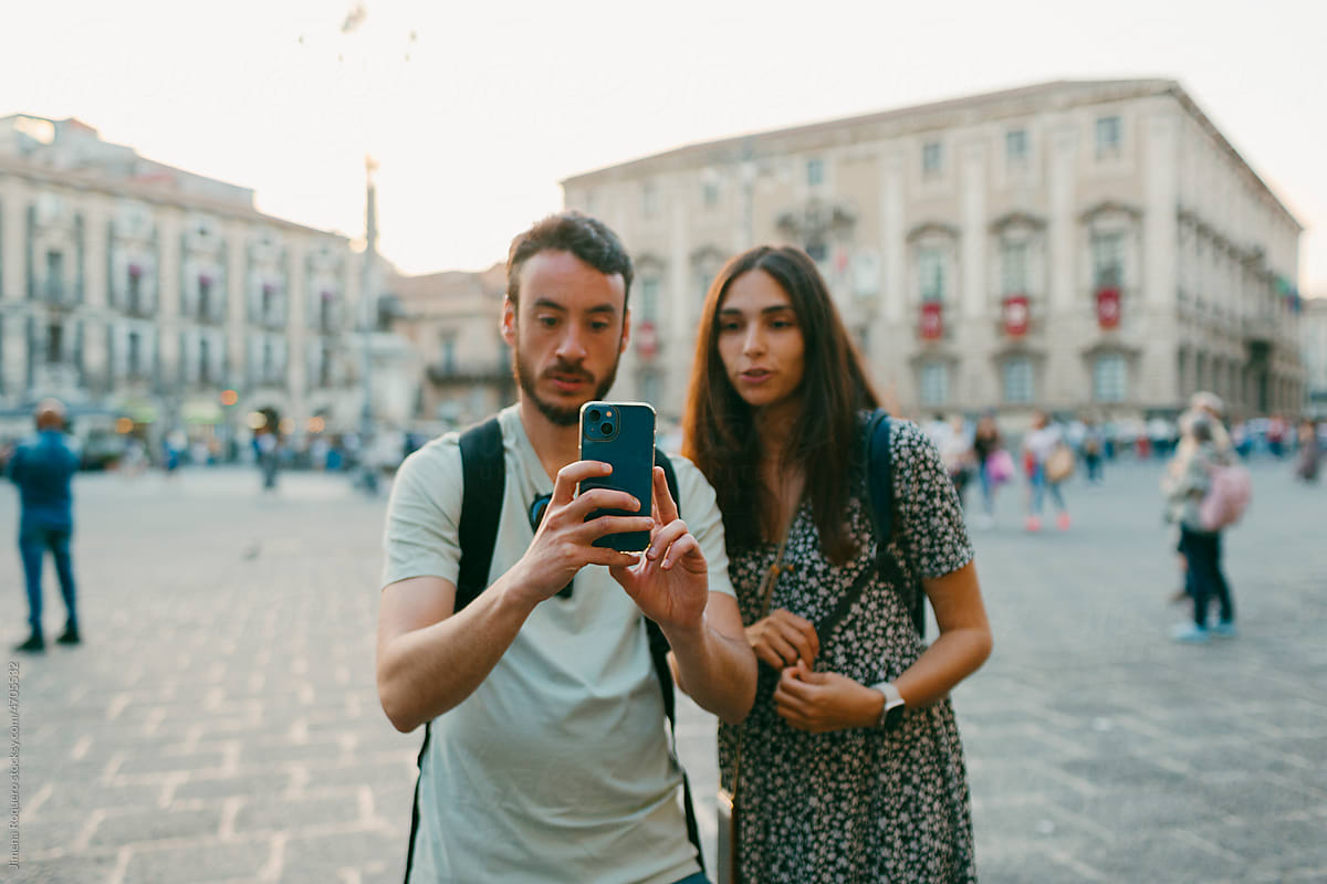 Young tourist couple taking a mobile photo in old Italian city square