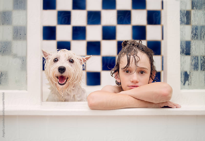 Young boy and small white dog enjoying a bath together
