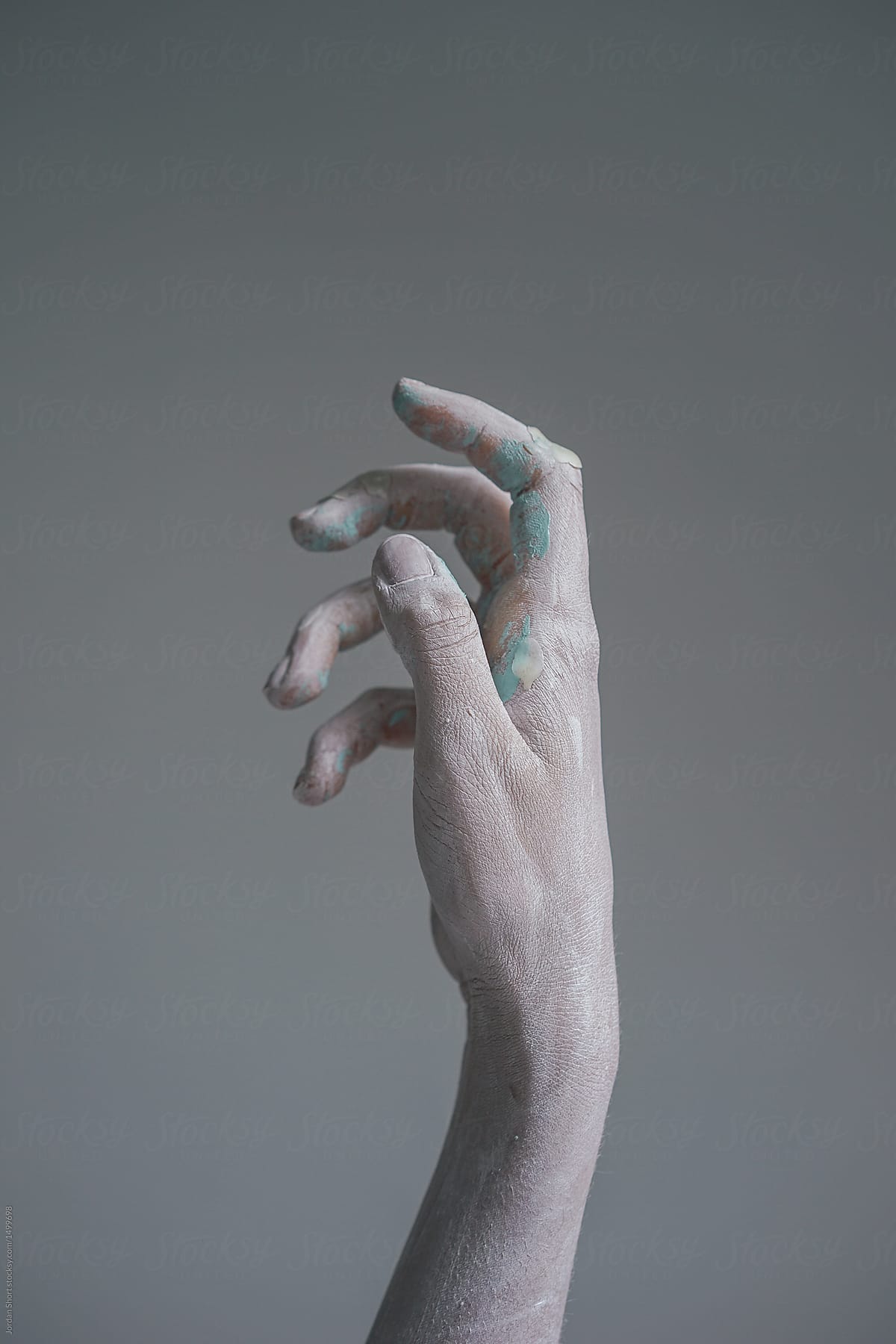 A white hand covered in blue candle wax