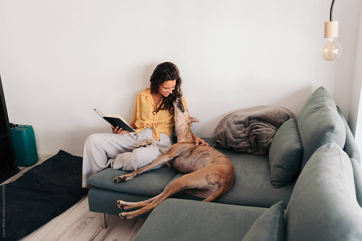 Woman reading a book at home with her dog