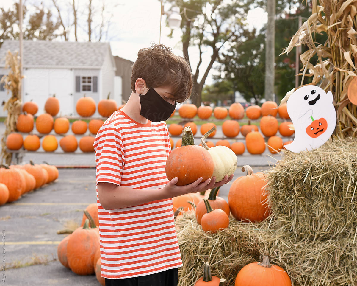 Boy in Face Mask Choosing Pumpkins for Sale