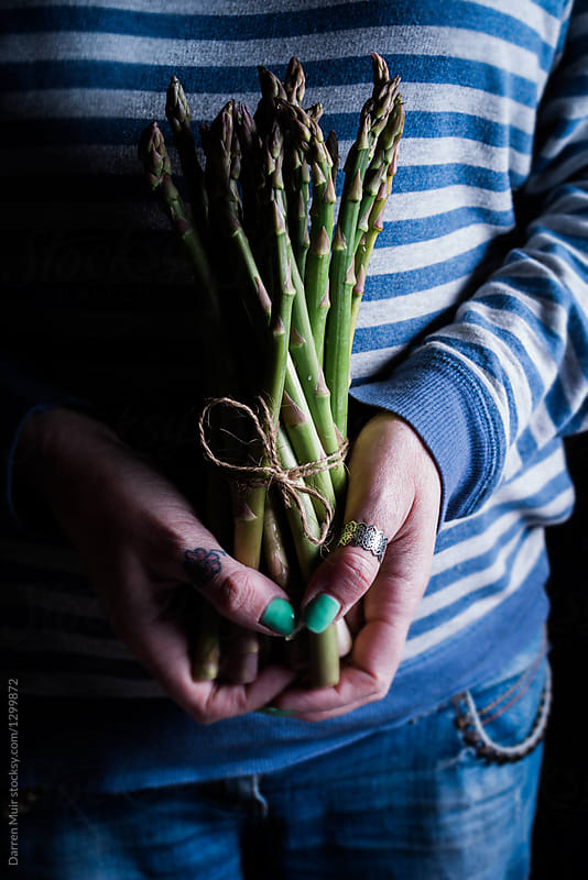 Woman\'s hands holding a bundle of asparagus.