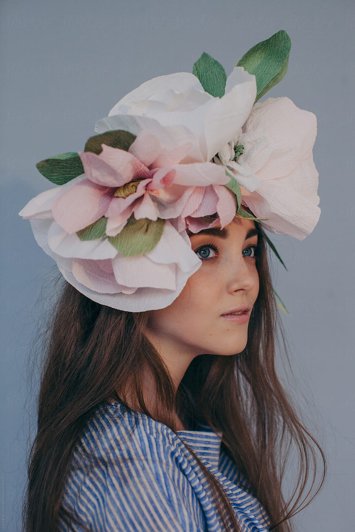 Side view portrait of beautiful woman with long hair wearing big paper flowers headdress