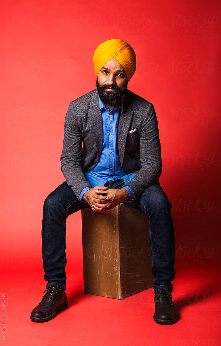 Portraiture of young handsome Indian Sikh against red background