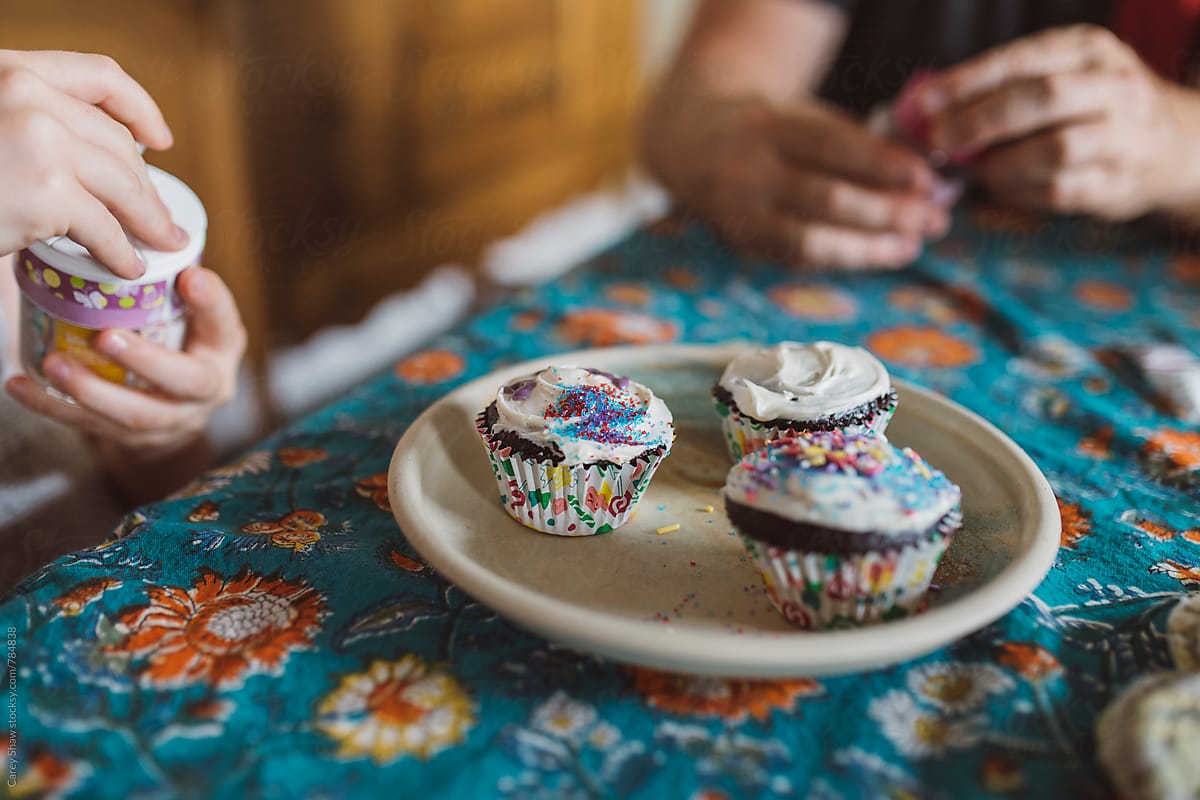 Closeup Of Father And Daughter Decorating Cupcakes By Carey Shaw