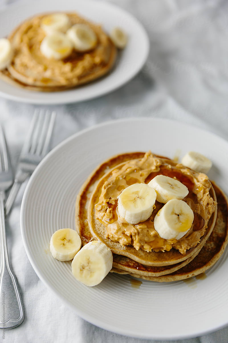 Two plates of vegan pancakes with peanut and banana
