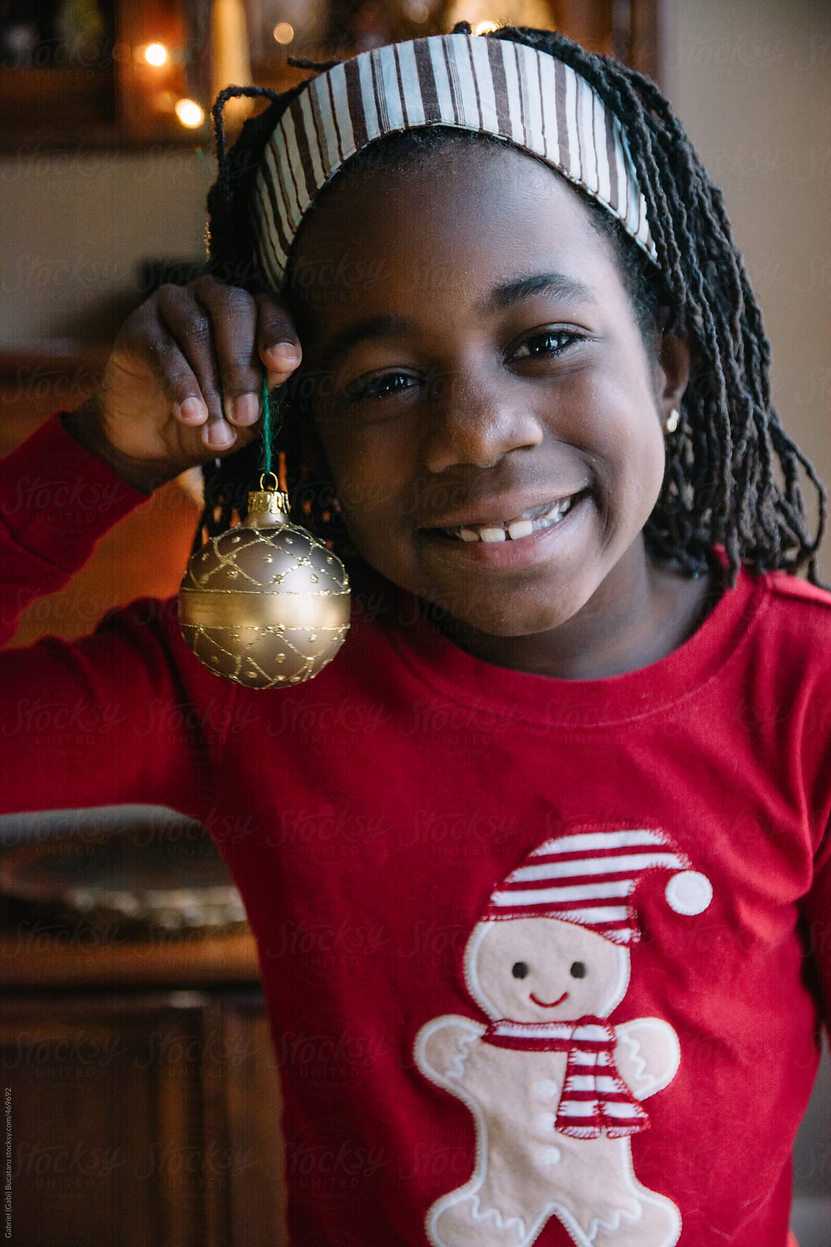 Black girl in ginger bread red pajama holding a Christmas decoration