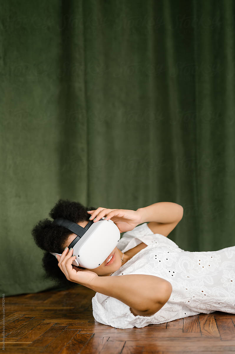 Amazed black woman in VR glasses resting on floor