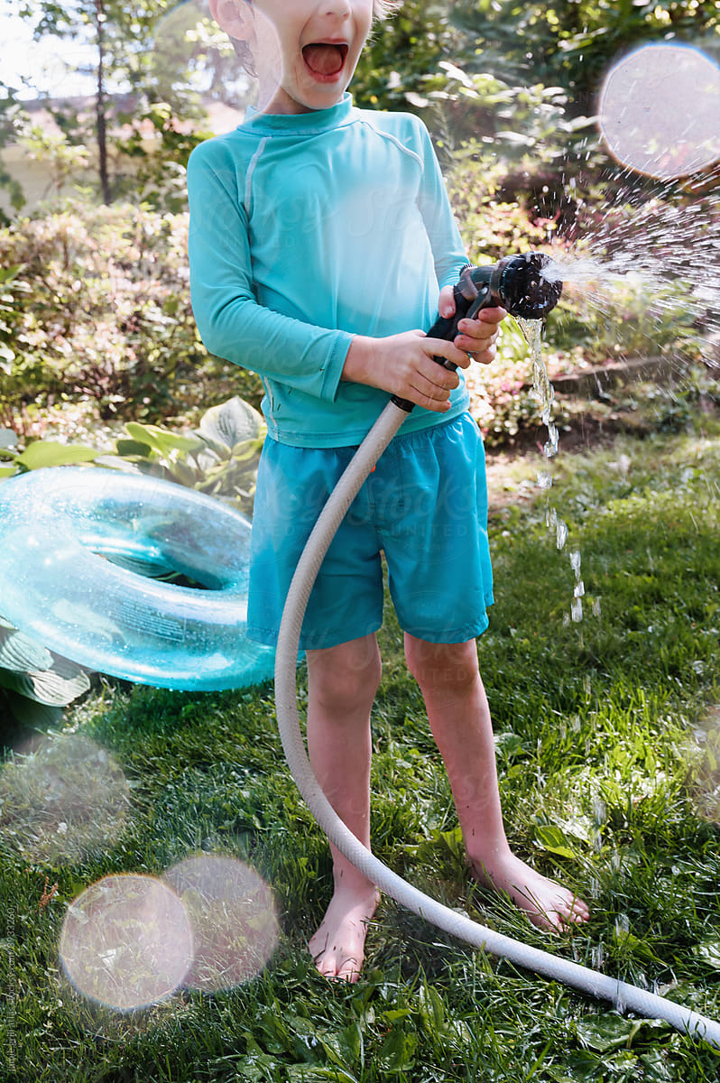 Boy Squealing with Delight as he Sprays a Hose