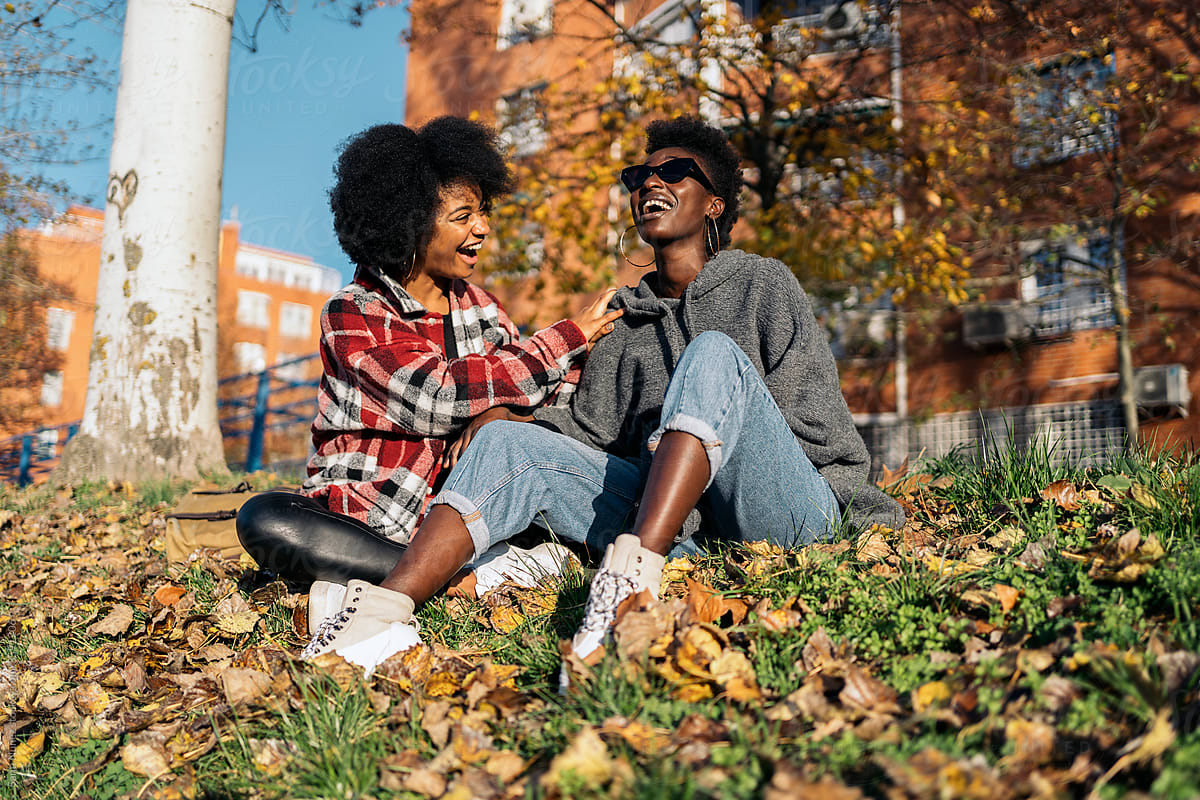 Content black girlfriends enjoying time in autumn park