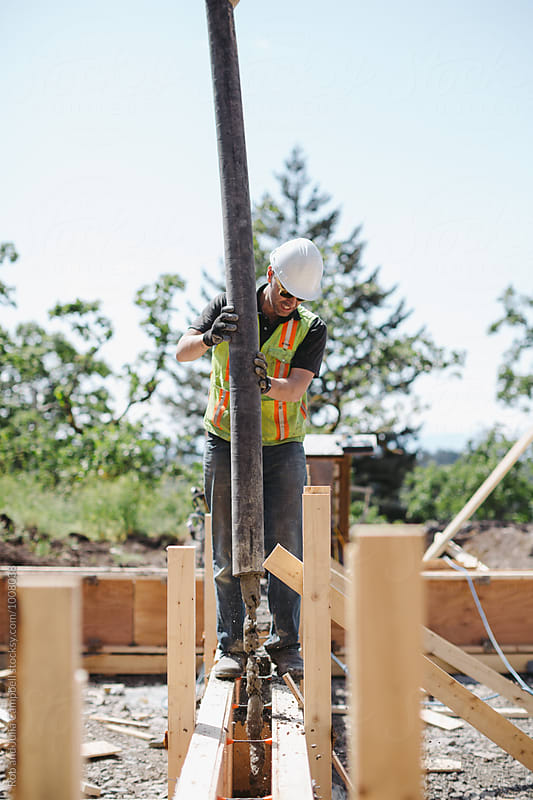 Construction builder pumping concrete into wood frame forms