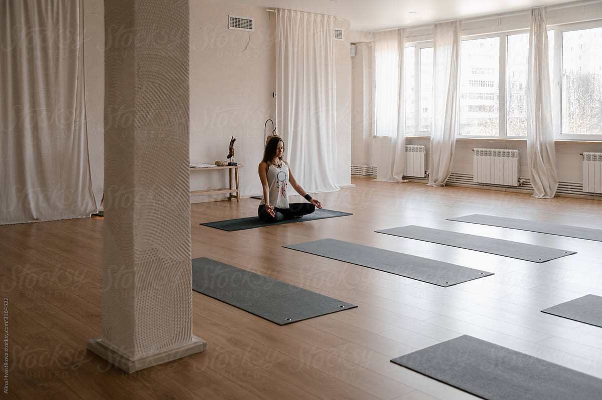 Yoga trainer meditating in empty studio
