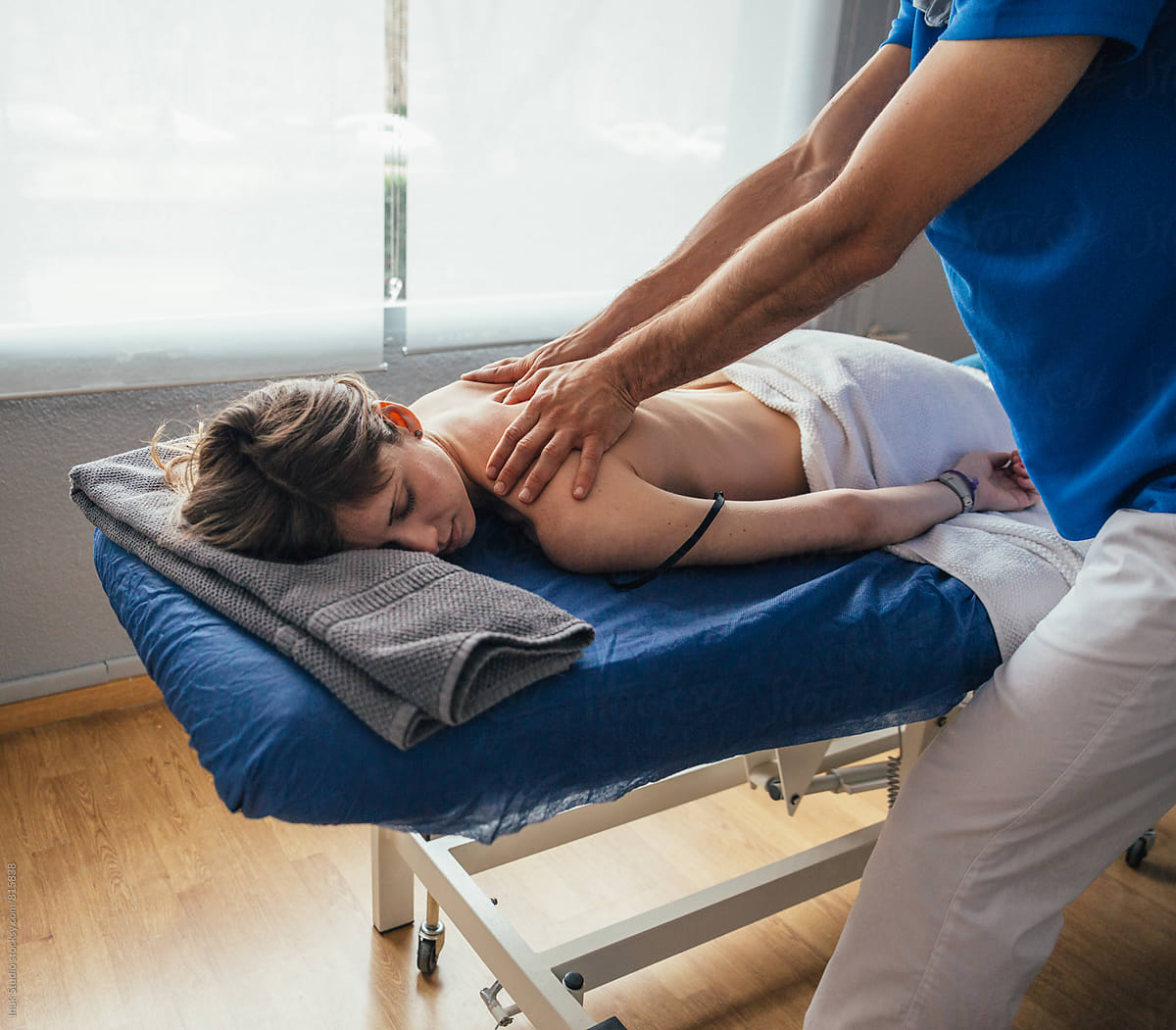 Young woman lying on her front on a medical bed receiving a massage during a physiotherapy session