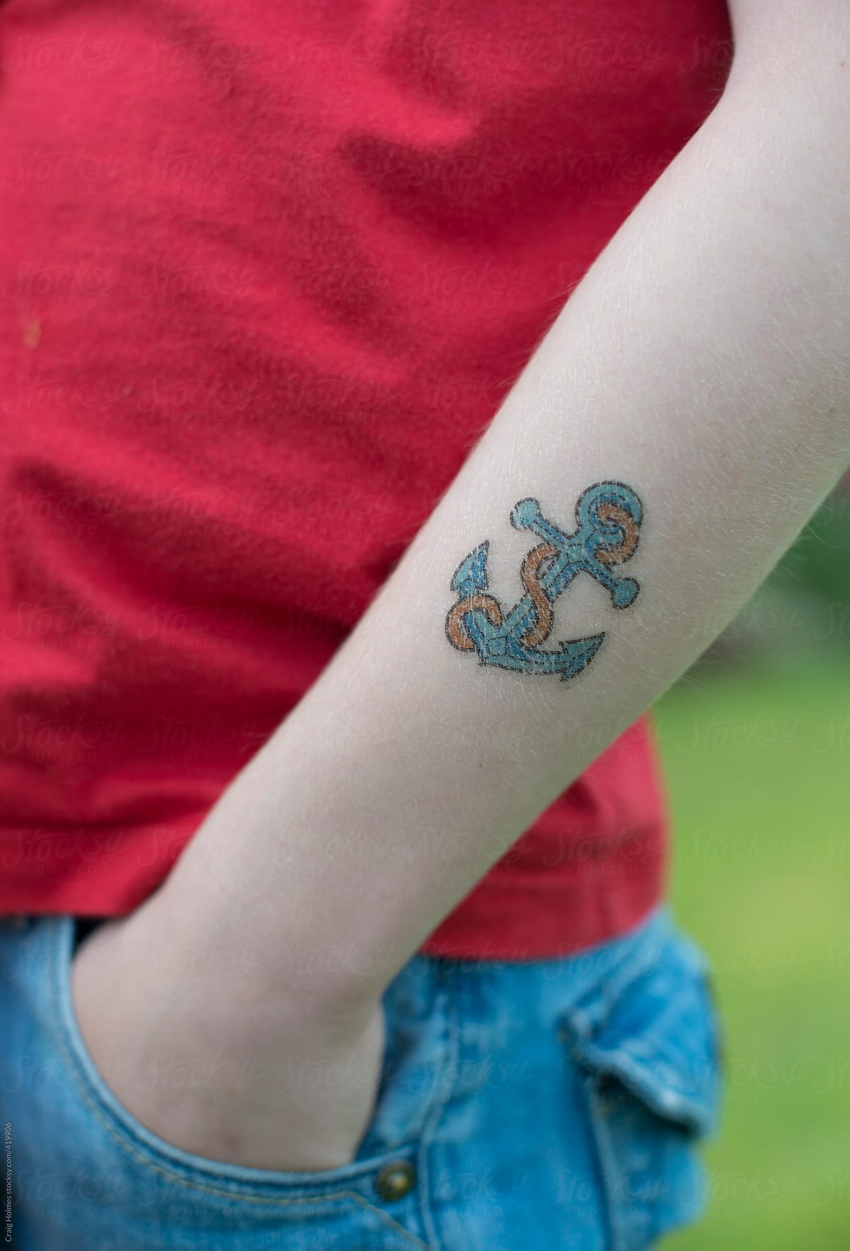 A boy with a temporary tattoo on his arm in the shape of an anchor.