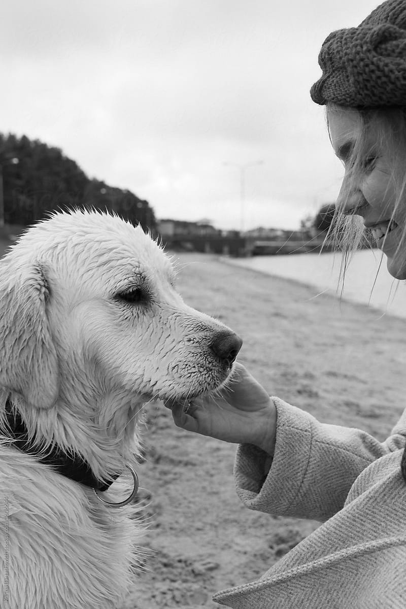 black and white portrait of a girl and a dog while walking near the lake and the hostess smiles happily at the dog