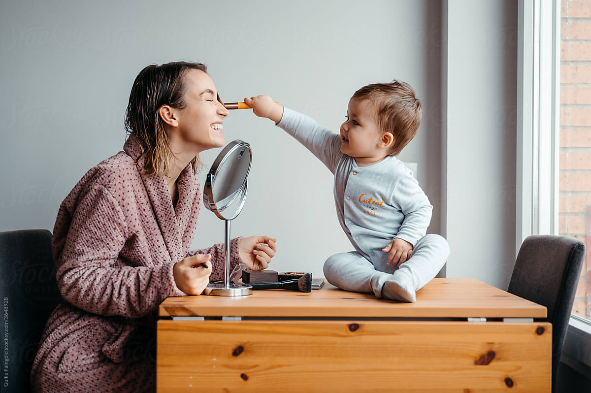 Mother and baby with cosmetic brush in morning