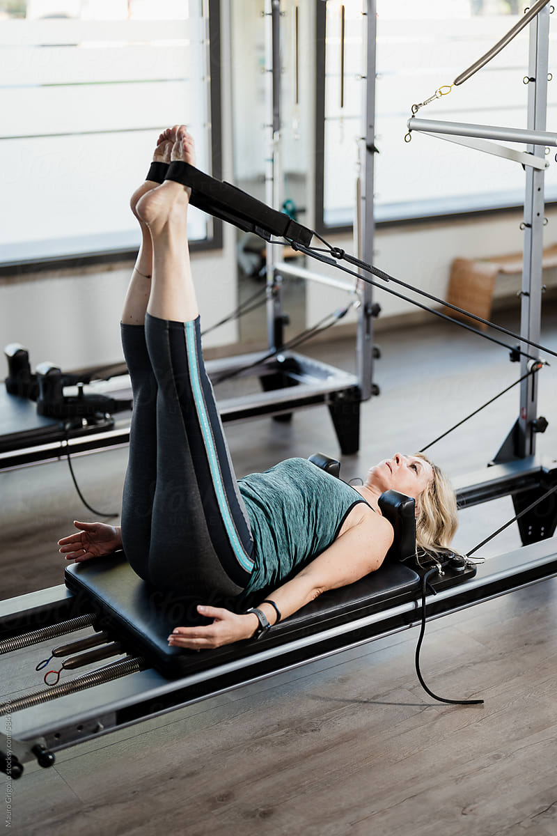 A mature woman doing pilates exercises in a gym