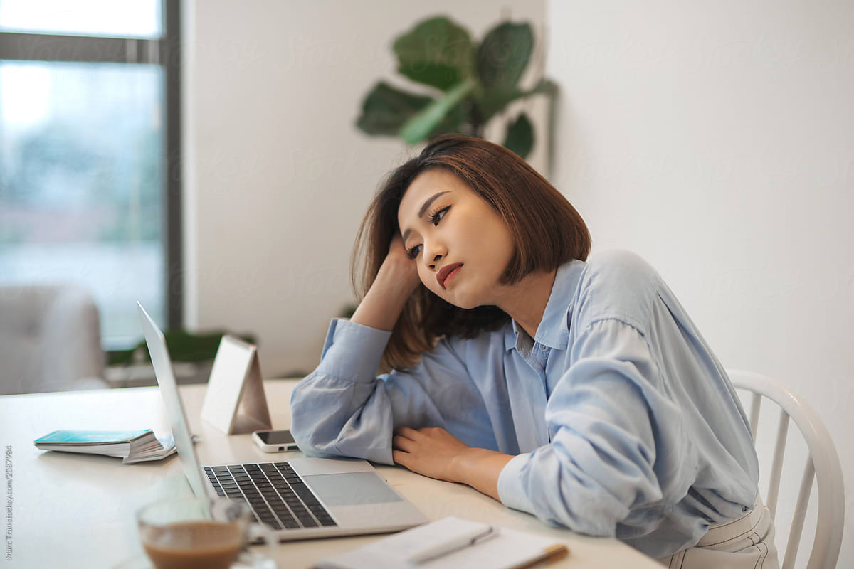 Bored millennial female worker lie at office desk