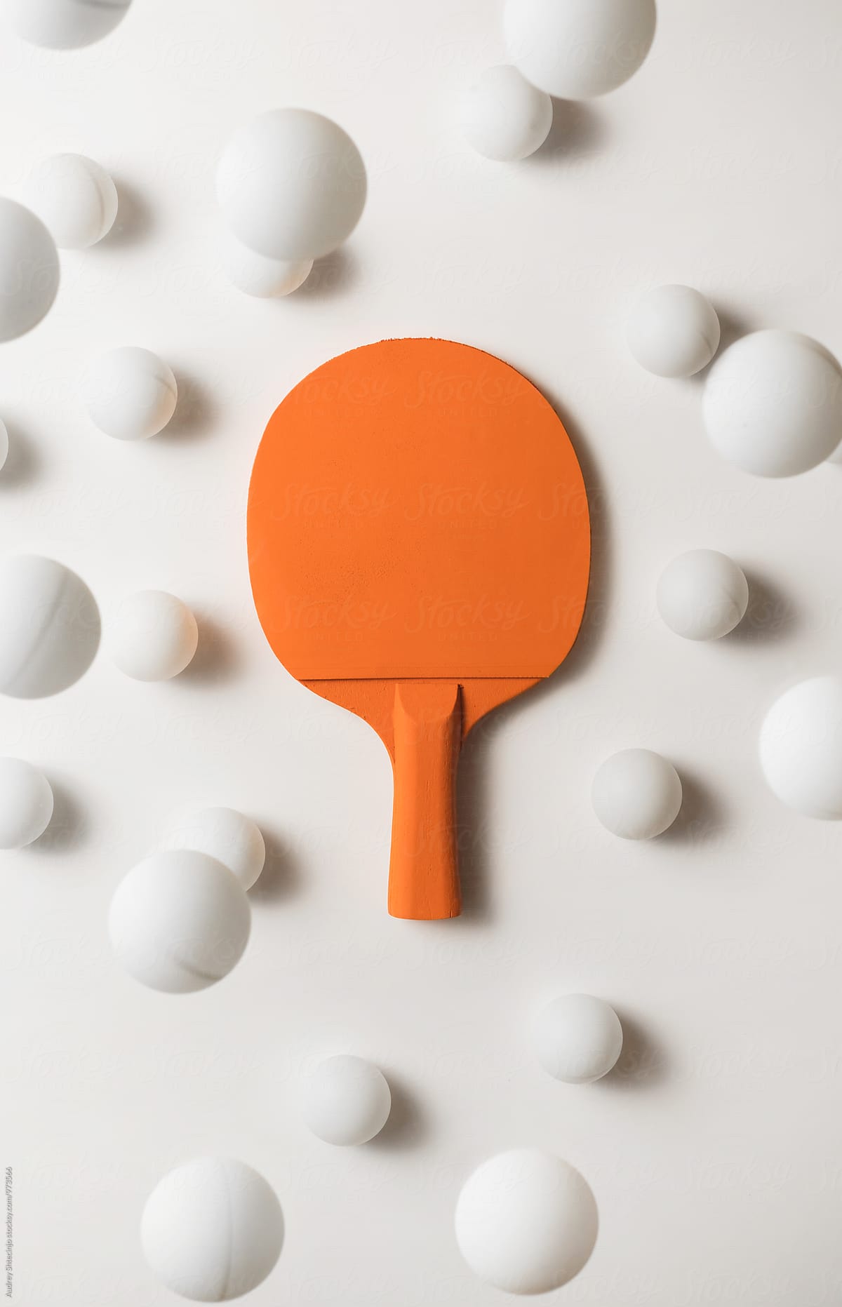 Orange pIng pong racket and white balls flying