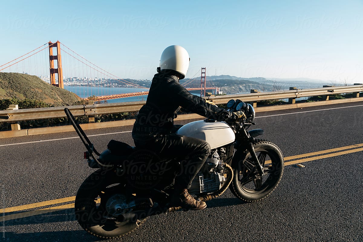 young man rides motorcycle with golden gate bridge in background