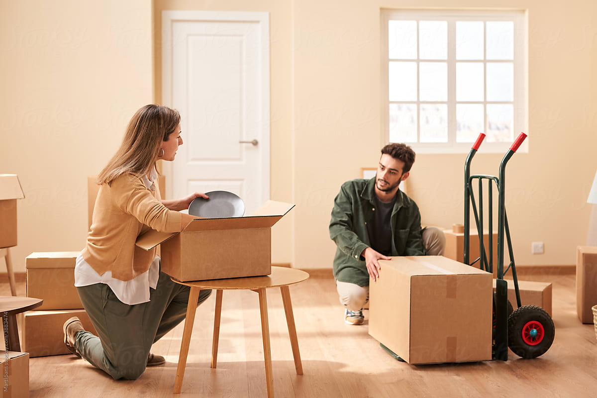 Couple with carton boxes and trolley in new apartment