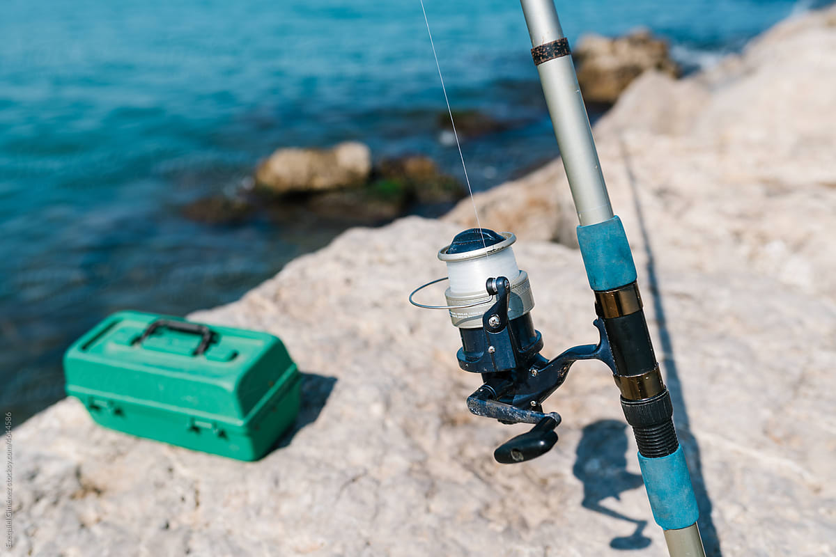 Fishing Rod With Reel And Line Near Sea In Sunlight by Stocksy