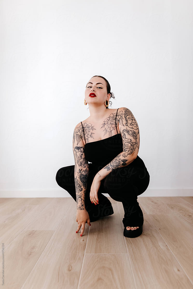 Tattooed woman squatting in studio