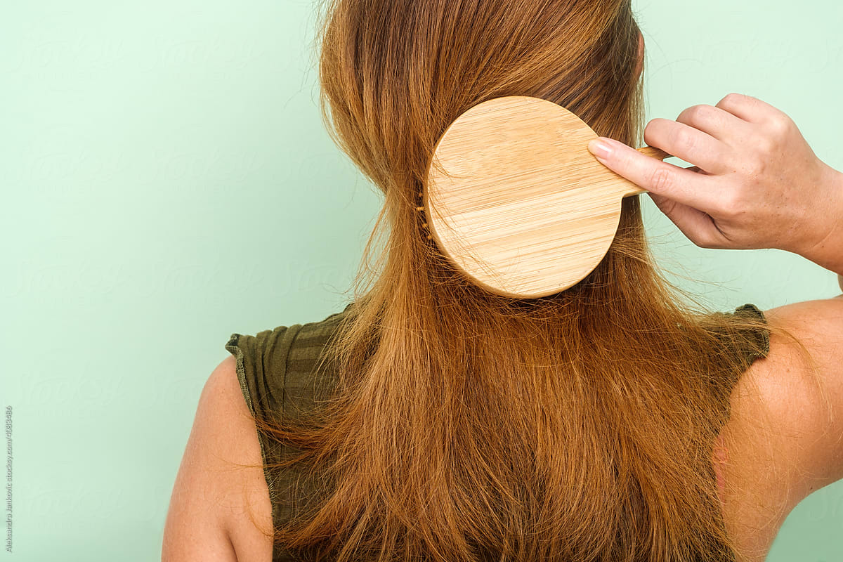 Back View Of Redhead Woman Using Wooden Hair Brush