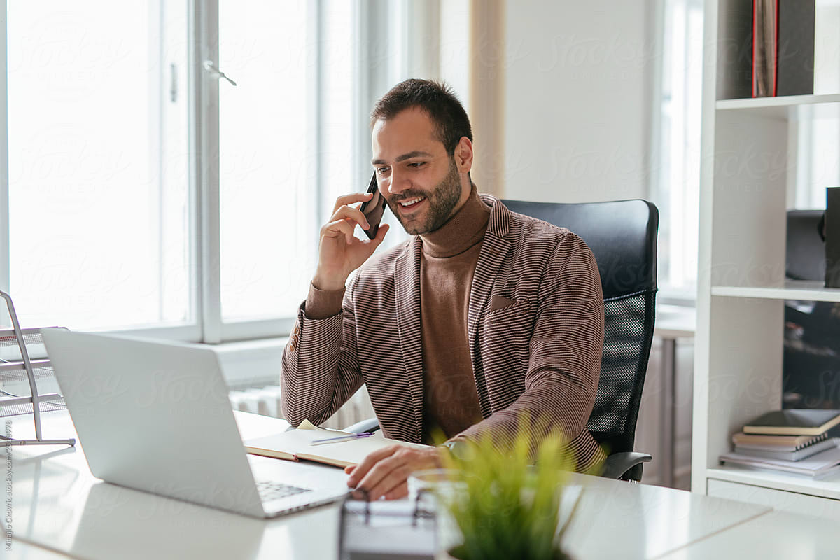 Stylish man working in office and talking on the phone