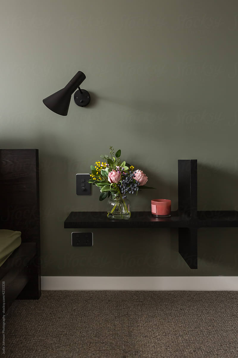 Bedside shelf of flowers with wall lamp