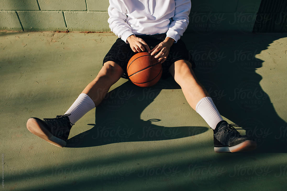 Anonymous man sitting on the floor of a basketball court