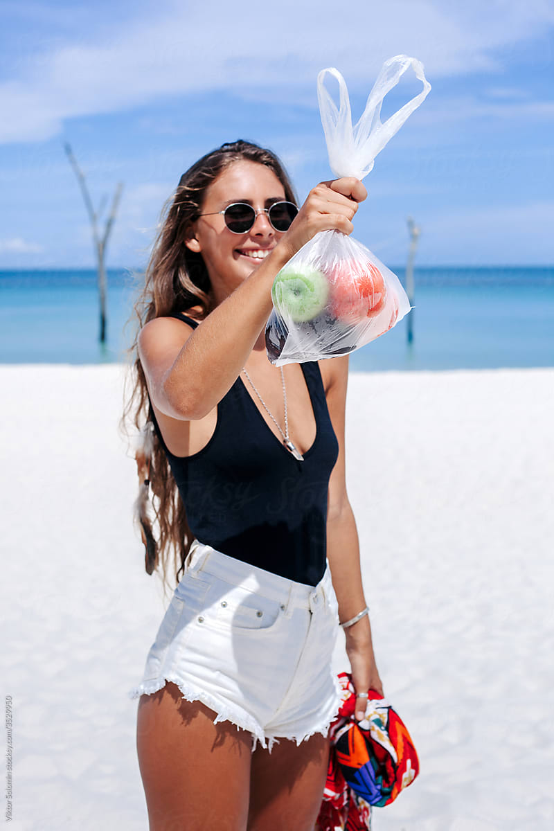 Happy woman with apples in bag on beach