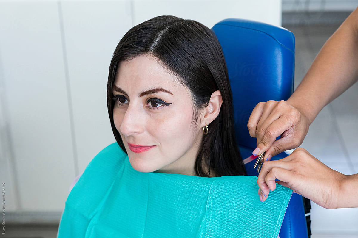 Female patient wearing an aqua colored bib sitting in a dental chair