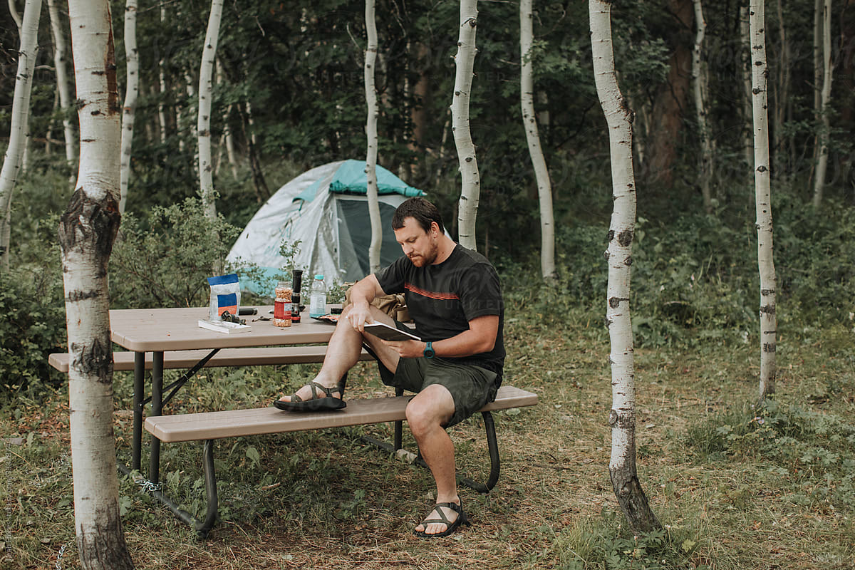 Man Reading Book at Campsite