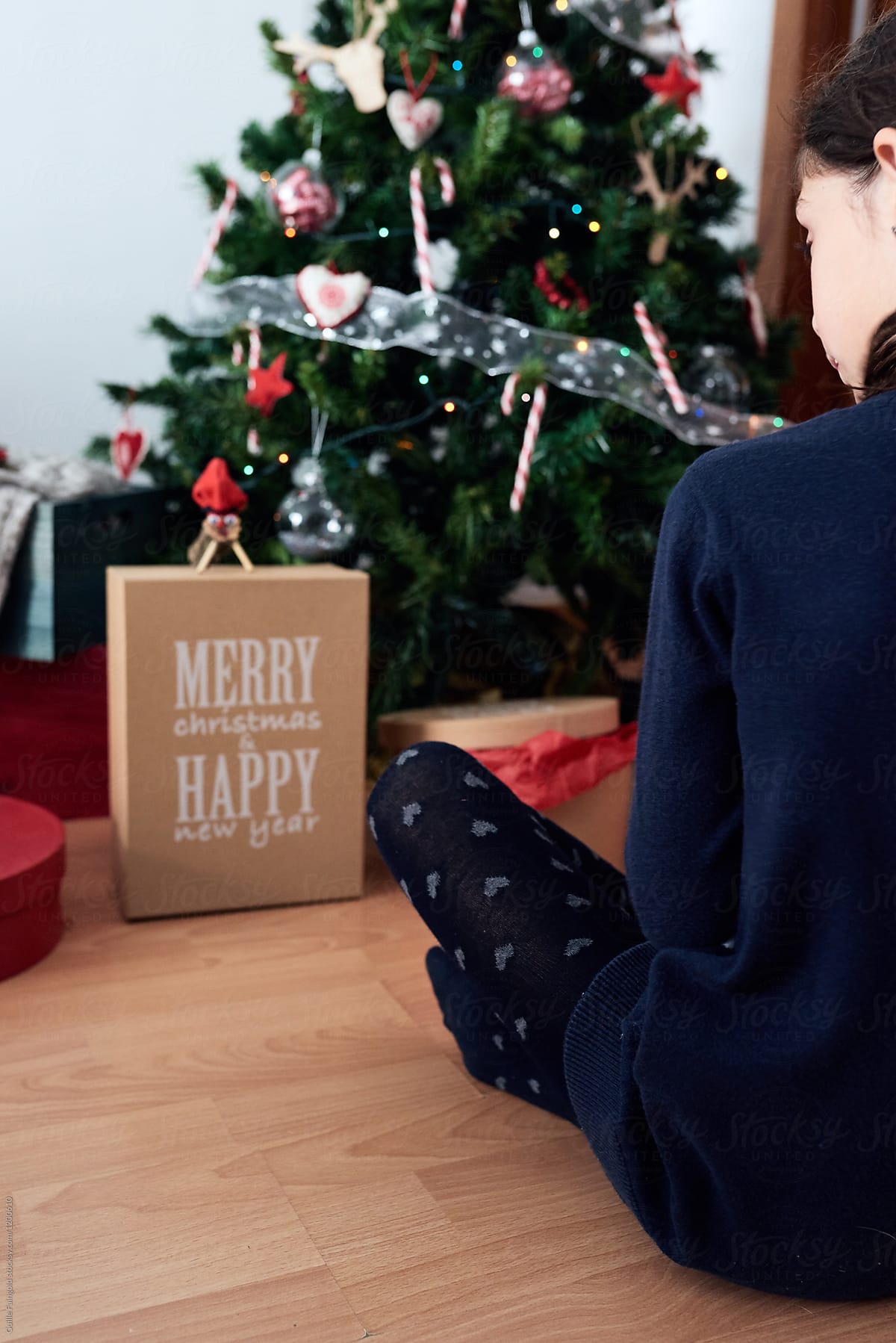 Girl in front of Christmas tree with presents