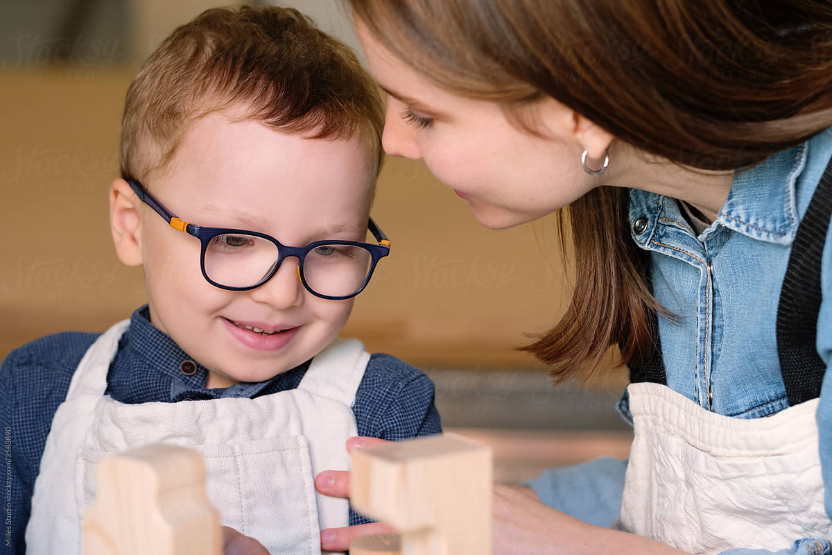 Cheerful little boy enjoying time with mom in carpentry workshop