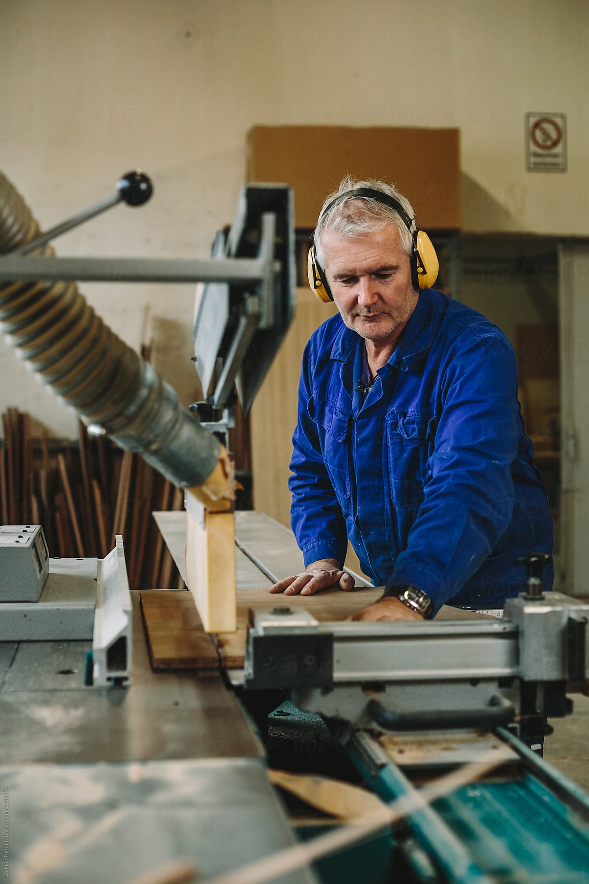 carpenter with yellow protection earmuffs working on a benchsaw