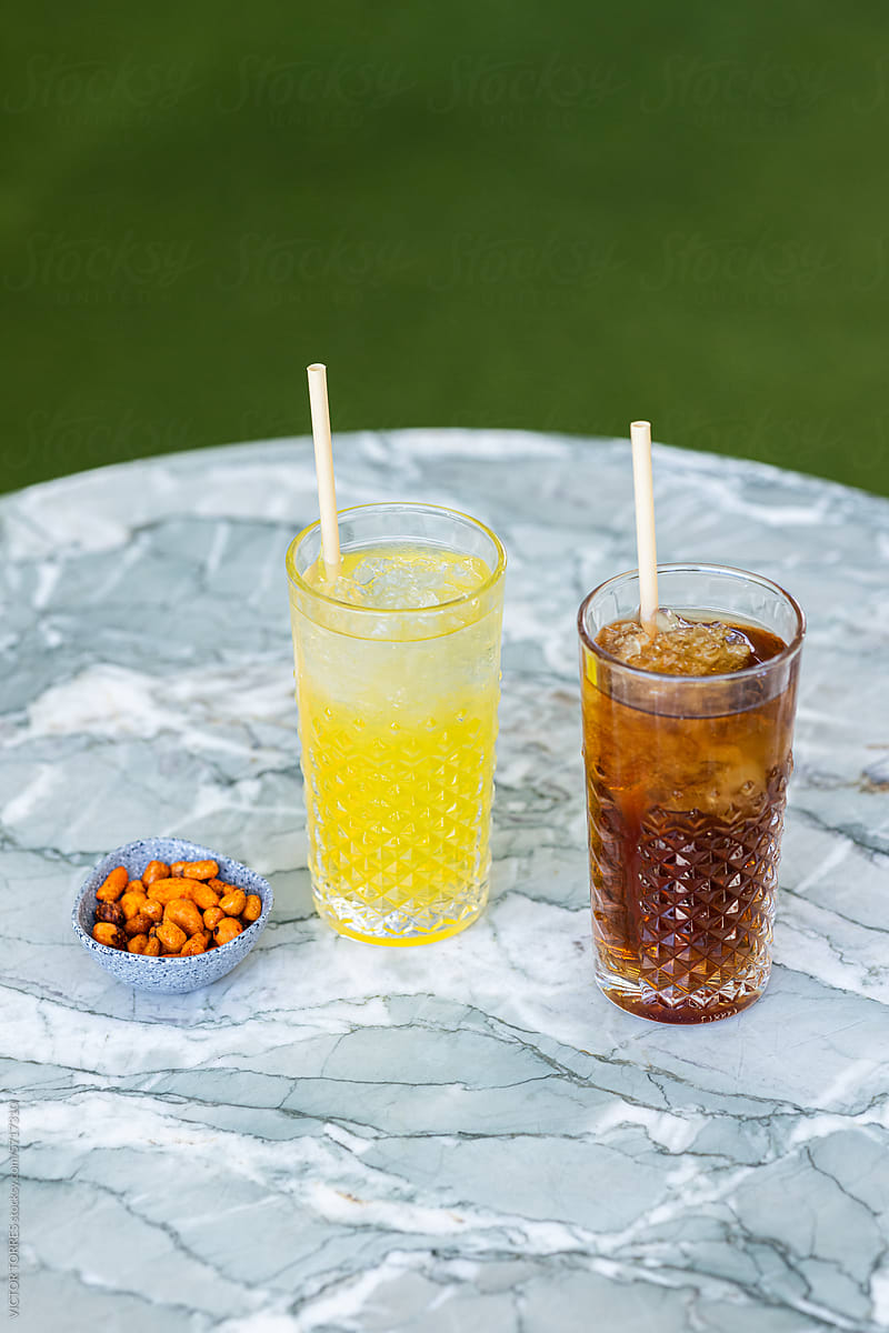 Two refreshing drinks with straws placed on a marble table