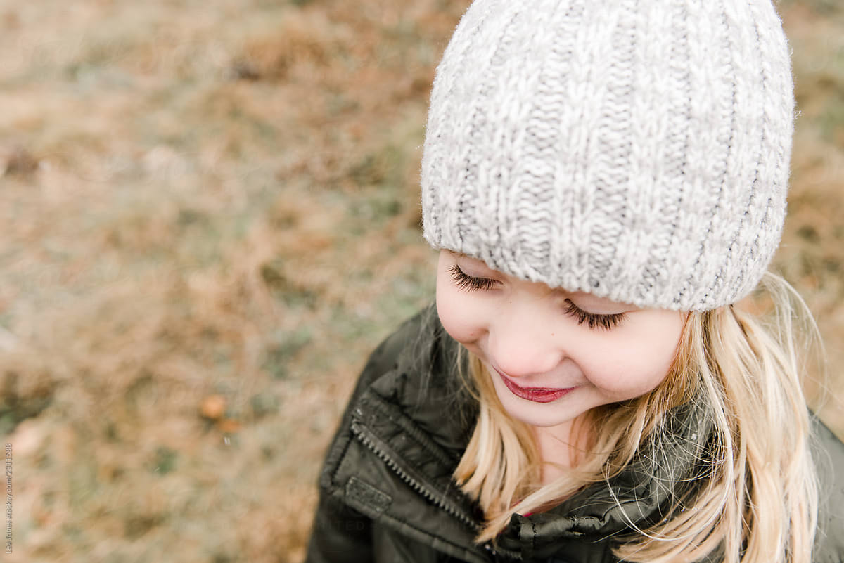 portrait little girl in big woolly hat in Christmas tree farm