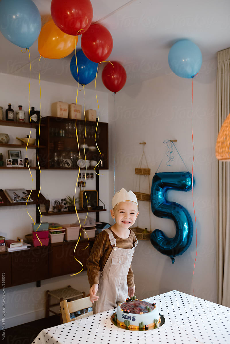 Toddler birthday boy with helium balloons indoors