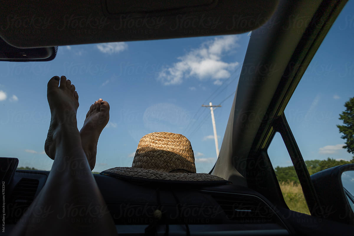 Woman\'s feet on dash of car traveling through Midwest scenery