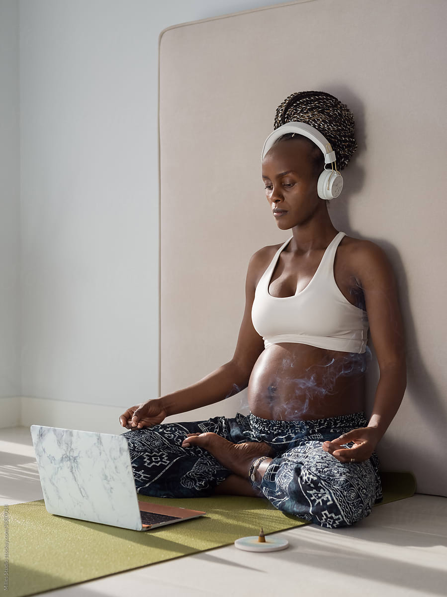 Pregnant female meditating with laptop and incense