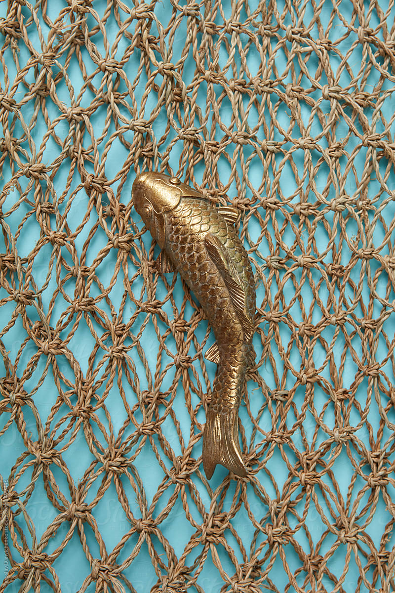 Goldfish from metal on a braided net background.