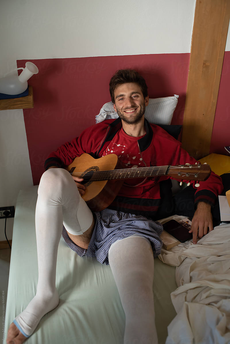 Smiling happy portrait recovering in bed injured young man