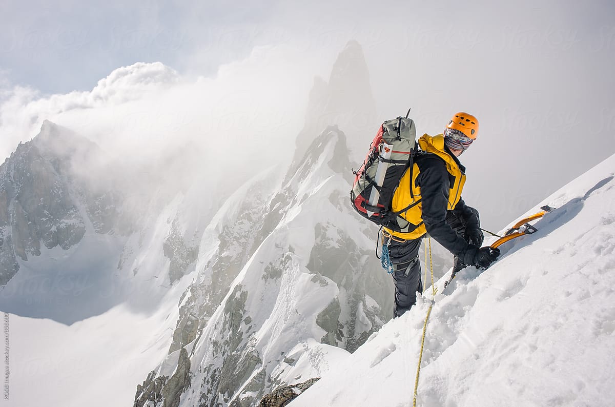 Mountaineer climbing a snow ridge at high altitude