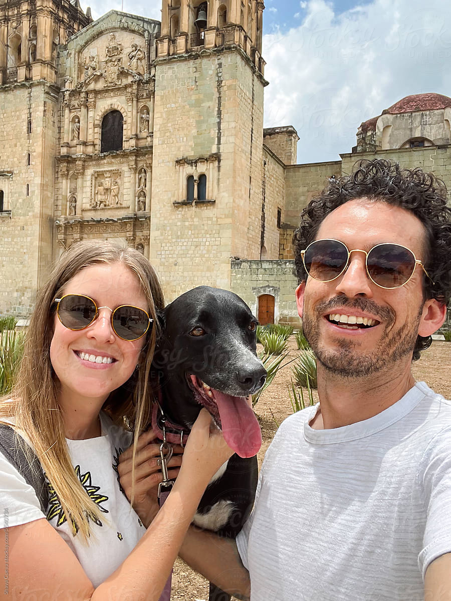 A happy couple takes a selfie with their black dog in Oaxaca Mexico