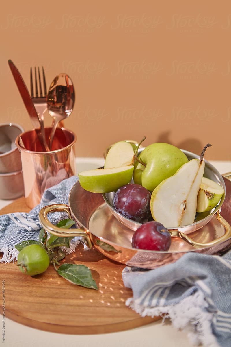 Still life with copper dinnerware and fresh fruits.