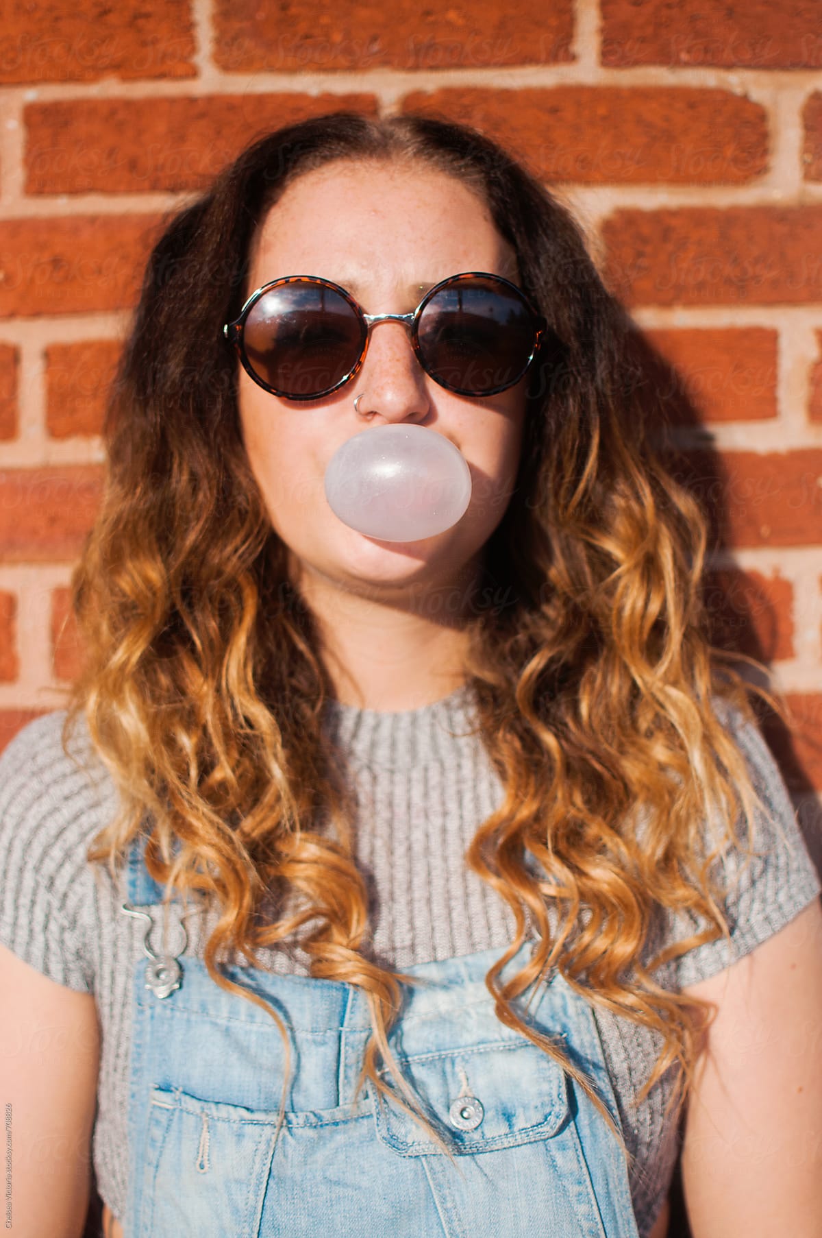 A young woman blowing bubble gum. 