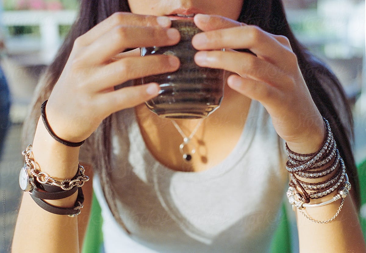 Pretty asian girl enjoying a cup of hot tea holding the cup in both hands