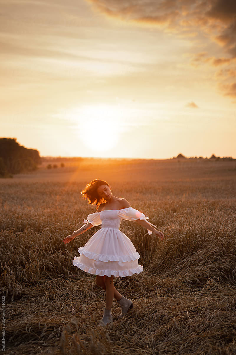 Girl in elegant garment dancing on meadow